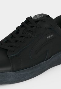 Baskets basses noires avec lacets à l'avant, semelle texturée et logo "REPLAY" sur le côté et la languette.