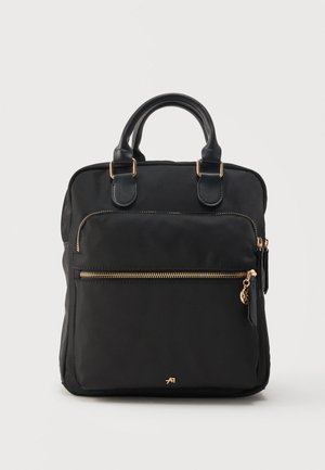 Sac à dos rectangulaire noir avec deux anses, poche avant zippée avec fermeture éclair dorée et tirette, et petit logo de marque doré en bas au centre.