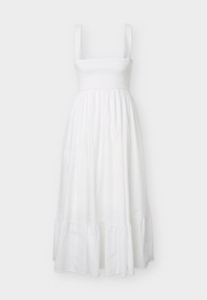 White sleeveless midi dress with smocked bodice and wide straps, featuring a gathered tiered skirt and ruffled hem.