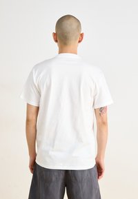 White cotton t-shirt with short sleeves and a crew neckline, displayed from the back, featuring no visible logo or patterns.