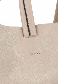 Beżowa skórzana torebka z teksturowaną powierzchnią. Posiada szyte akcenty i dwa uchwyty, z minimalistycznym wzornictwem i bez dodatkowego osprzętu.