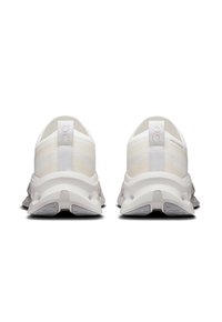Încălțăminte sportivă albă cu un superior din plasă texturată, cu un tab de călcâi moale și o talpă interioară căptușită, care prezintă decupaje pentru ventilație.