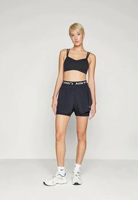 Top desportivo preto e calções com um logótipo Nike branco, feitos de um tecido leve, com um cós elástico e um ajuste atlético.