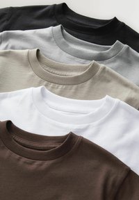 Fünf Crewneck-T-Shirts ordentlich gestapelt in den Farben Schwarz, Grau, Beige, Weiß und Braun auf einer hellen Oberfläche.