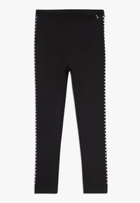 Zwarte legging van een gladde, rekbare stof met zilveren studs langs de buitennaad. Enkel lengte met een strakke pasvorm.
