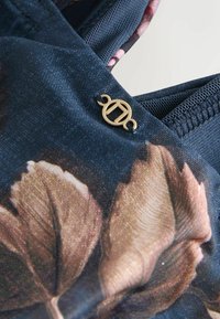 Tessuto blu navy con un motivo floreale arricchito da accenti dorati. Il tessuto ha una texture liscia con dettagliate foglie disegnate.