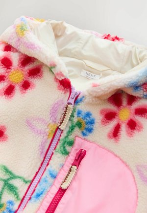 Veste à capuche en polaire avec un motif floral en rose, jaune et bleu sur fond crème. Comprend une fermeture éclair rose et des accents de poches.