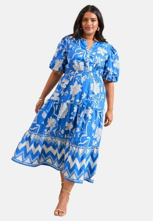 Blaues florales Maxikleid mit Puffärmeln, geraffter Taille, gestuftem Saum und Zickzackmuster am unteren Rand. Hergestellt aus leichtem Stoff.