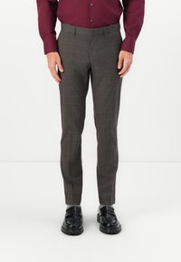 Brown plaid trousers with a tailored fit, flat front, and side pockets. Worn with a maroon long-sleeve shirt and black shoes.