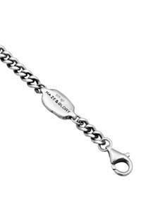 Bracciale in argento con maglie piatte e intrecciate, un'etichetta ovale strutturata contrassegnata con "HAZE & GLORY" e chiusura a gancio.