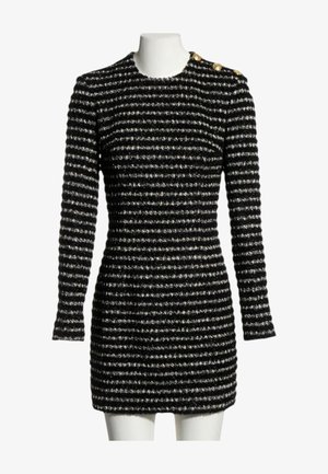 Mini-robe rayée noire et argent à manches longues avec col rond et quatre boutons dorés sur l'épaule gauche, présentée sur un mannequin blanc.