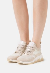 Beżowe sneakersy z mieszanką zamszu i skóry, okrągłym noskiem, wyściełanym kołnierzem oraz teksturowaną gumową podeszwą z złotymi akcentami.