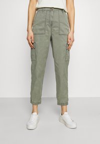 Svetle olivově zelené cargo kalhoty s uvolněným střihem, které mají několik kapes a elastické manžety. Vyrobeny z pružné bavlněné tkaniny.