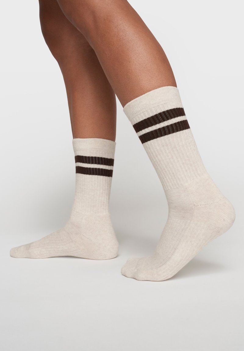 Calzini beige a costine con due strisce marroni in cima. Caratterizzati da un design con tallone e punta rinforzati. Realizzati in morbido materiale misto cotone.