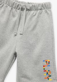 Grå bomulds sweatpants med elastisk talje og snor. Har flerfarvet geometrisk broderi på nederste del af benet.
