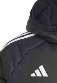 Svart polstret jakke med fleece-fôret hette, med hvite striper på armene og en hvit trekantet logo på brystet.