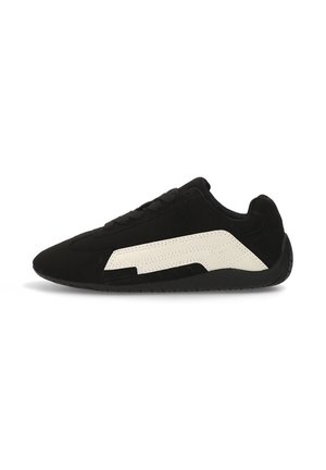 Zapatilla de ante negro con un acento de cuero blanco texturizado; diseño de perfil bajo, punta redonda y cuello acolchado para mayor soporte.