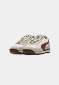 Beige suede and fabric sneakers with maroon accents, round toe, flat rubber sole, and padded collar. Features a logo on the tongue.