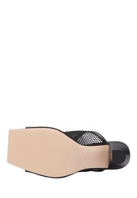 Zwarte mesh schoen met een brede teenruimte, open achterkant en een gladde beige zool. Heeft een rechthoekige hak en een strakke minimalistische uitstraling.