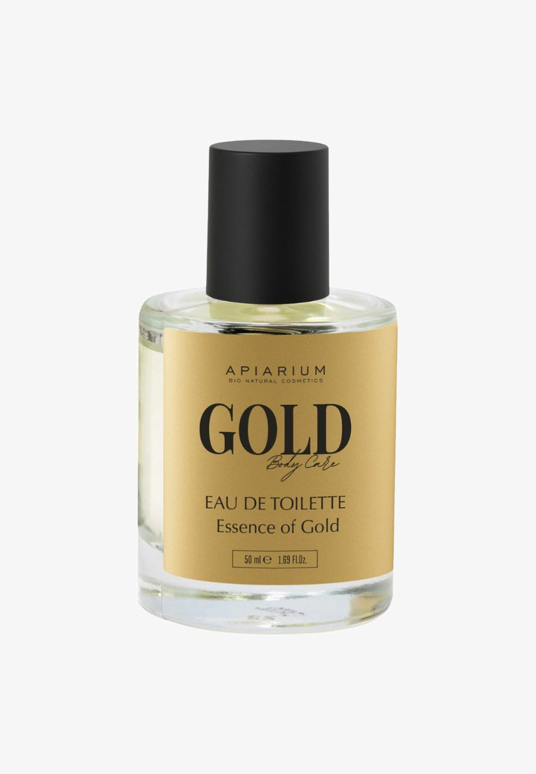 Bottiglia di vetro trasparente con un tappo nero, dotata di un'etichetta dorata con la scritta "GOLD Body Care." Contiene 50 ml di Eau de Toilette, "Essence of Gold."