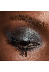 Nærbilde av et øye med sølv- og mørkegrå øyenskygge, definerte vipper og en jevn, mørk hudtone rundt øyet.