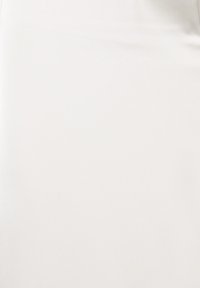 Tissu blanc uni avec de subtiles rides et des ombres douces sur une surface lisse.
