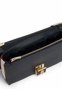 Schwarze Lederhandtasche mit goldenen Beschlägen und strukturierter Oberfläche. Verfügt über einen Reißverschluss und ein Innenfach. Akzente in Rot und Creme.