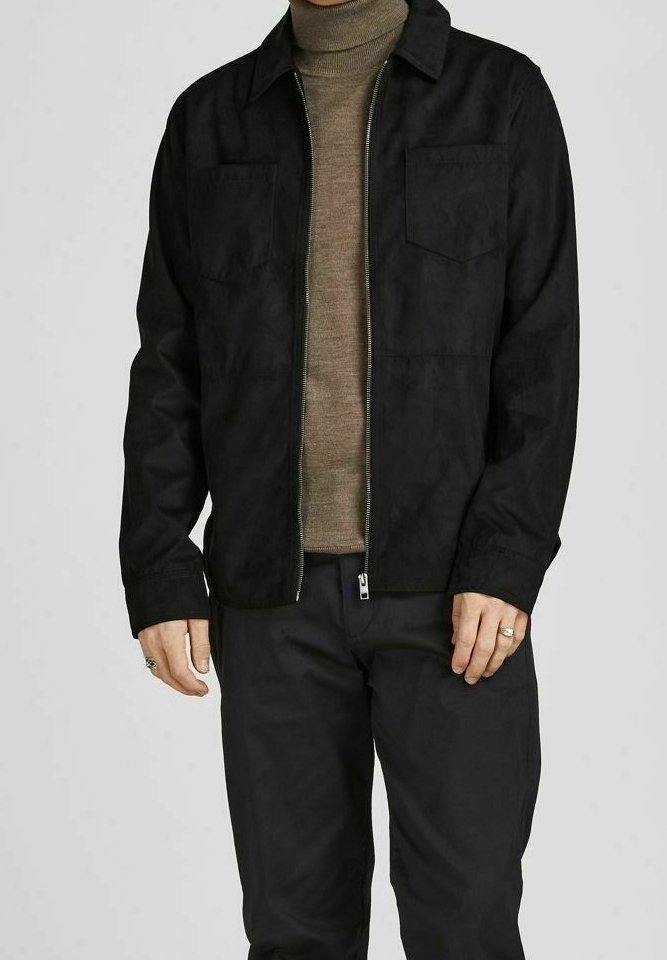 Schwarze Jacke mit Reißverschluss aus glattem, strukturiertem Stoff, mit zwei Fronttaschen und einem Kragen, getragen über einem hellbraunen Rollkragenpullover.