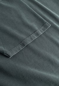 Czarny szary t-shirt z materiału o gładkiej fakturze, z płaskimi szwami na rękawach i subtelnym połyskiem dzięki wysokiej jakości materiału.