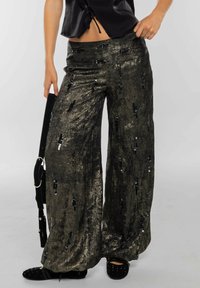 Pantalon large noir métallique avec une texture scintillante et des accents pailletés, doté d'une ceinture confortable et d'un design fluide.