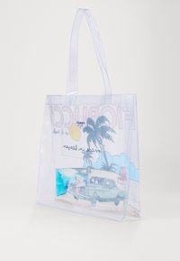 Sac fourre-tout transparent avec un motif coloré sur le thème de la plage, comprenant des palmiers et une voiture vintage, rehaussé de nuances de bleu et de lettrage audacieux.