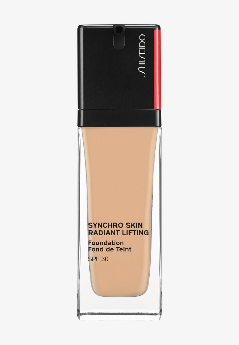 Shiseido Synchro Skin Radiant Lifting -meikkivoidepullo mustalla kannella, punaisella yksityiskohdalla, beige nestemäinen meikkivoide, SPF 30 -merkintä.