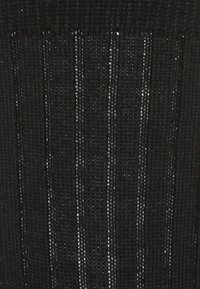 Tessuto nero intrecciato con fasce verticali e occasionali fili argentati a contrasto per dettagli di texture e motivo.