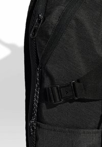 Mochila negra con un tejido texturizado, múltiples cremalleras, correas ajustables y un bolsillo lateral con cierre de hebilla.
