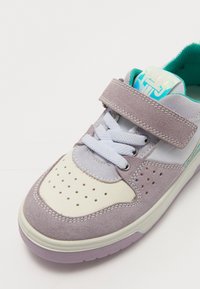 Lila és krém színű sneaker, velúrból és hálós anyagból készült felsőrésszel, fehér fűzőkkel, állítható pánttal és türkiz színű részlettel a nyelvén.