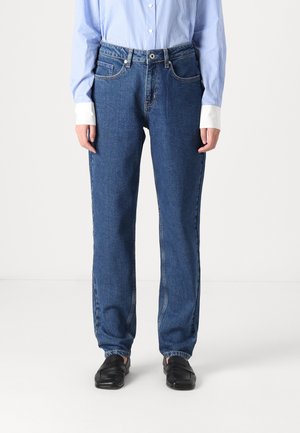 Blue denim jeans with a straight fit, high waist, and two front pockets. Worn with a light blue striped button-up shirt and black shoes.
