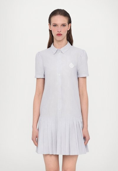 Striped shirt dress in light blue and white with a collared neckline, short sleeves, button front, and pleated skirt. Features embroidered logo.