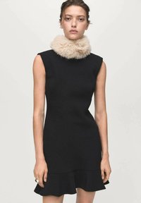 Black fitted dress with a rounded neck, short sleeves, and flared hem. Accented by a light faux fur collar for texture contrast.