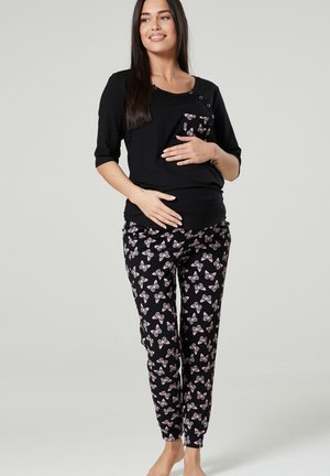 Black pajama set featuring a short-sleeve top with a pocket and decorative butterfly print pants in pink and white against a black background.