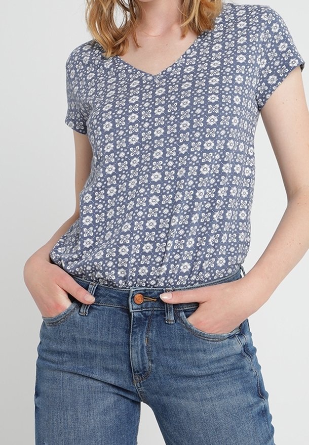 Top corto de manga corta con estampado floral azul y diseño de escote en V, combinado con jeans de mezclilla azul. La tela parece suave y ligera.