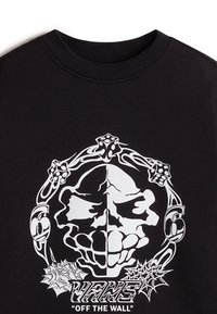 Maglietta nera in cotone, con una grande grafica bianca di un teschio, dadi e disegni di ragnatela, insieme al testo "VANS OFF THE WALL".