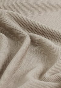 Beige ribbet stof med en blød tekstur, der viser en subtil glans og et ensartet mønster af fine linjer på overfladen.