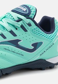 Lys teal atletisk sko med mørkeblå accenter, mesh ventilationssystem og teksturerede materialer. Har en afrundet tå og snøresystem.