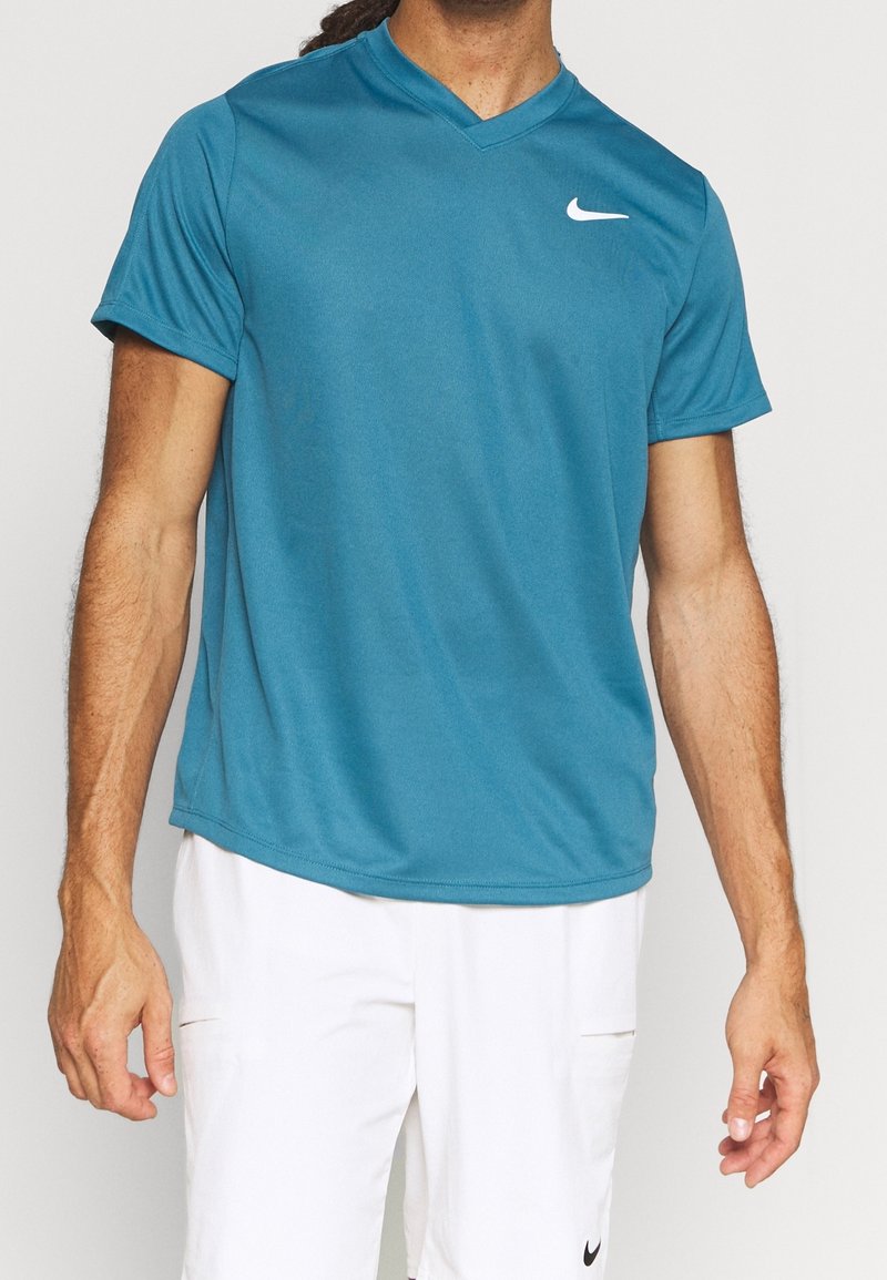 Tyrkysové sportovní tričko Nike s krátkým rukávem a výstřihem do V. Obsahuje malé bílé logo swoosh na horní levé části hrudi. Hladká textura.