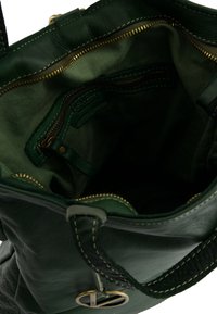 Grünes Leder-Stoffbeutelinnere mit goldfarbener Reißverschluss, einer Reißverschlusstasche und einem Stofffutter. Merkmale kräftige Nähte und einen dekorativen Hardwareakzent.