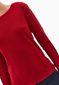 Czerwona koszula z długim rękawem wykonana z miękkiego materiału, z okrągłym dekoltem, przeszytymi detalami i luźnym krojem. Idealna na codzienne noszenie.