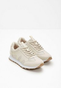 Scarpe da ginnastica beige realizzate in rete e suede, con un design testurizzato, punta rotonda, chiusura con lacci e suola in gomma bianca.
