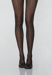 Collants noirs à pois avec une texture transparente ; petits pois ronds régulièrement espacés ; associés à des escarpins noirs ouverts à l'avant sur une surface lisse.