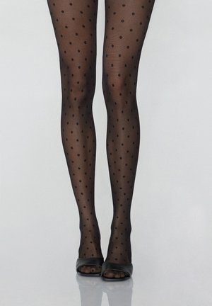 Schwarze Punktestrumpfhosen mit transparenter Textur; kleine runde Punkte gleichmäßig verteilt; kombiniert mit schwarzen offenen High Heels auf einer glatten Oberfläche.