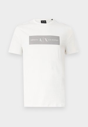 Tricou alb cu mâneci scurte, design dreptunghiular cu dungi negre și textul "Armani Exchange" pe piept, guler rotund și etichetă neagră cu brand pe guler.
